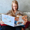 Eine Mutter lächelt und liest das personalisierte Buch ihren Söhnen vor. 