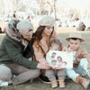 Eine Familie im Park zeigt ihr personalisiertes Buch für Familien mit 2 Kindern von Hurra Helden. 