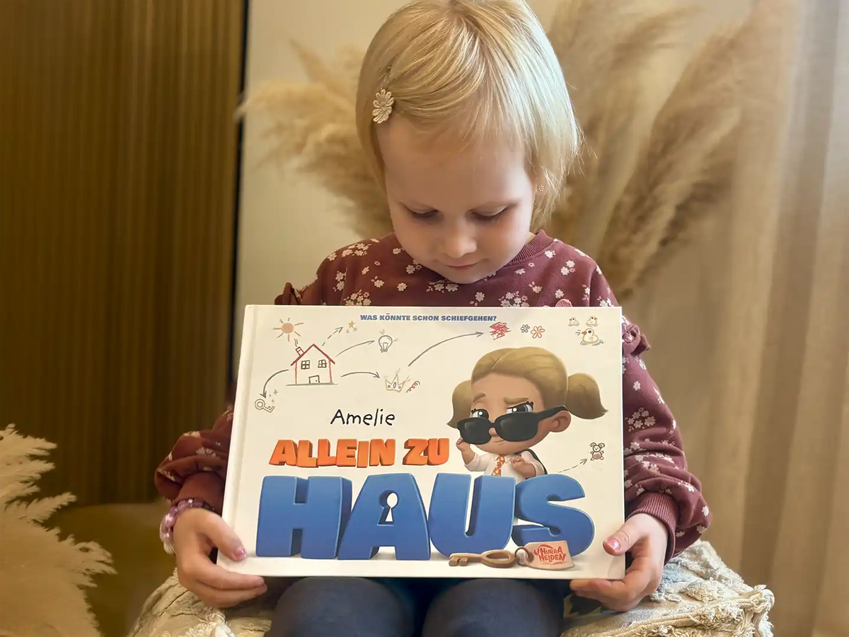Ein kleines Mädchen hält ihr neues personalisiertes Buch „Allein zu Haus“ in der Hand.